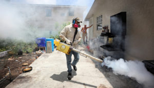 Carlos Varas, a Miami-Dade County mosquito inspector, sprays around homes in the Wynwood area of Miami on Tuesday, Aug. 2, 2016, as 14 cases of Zika have been found in the area. (Emily Michot/Miami Herald/TNS via Getty Images)